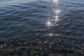 Sun glare and colorful  pebbles in the clear morning water of lake baikal, ripples, coast Royalty Free Stock Photo
