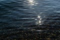 sun glare and emerald gold colorful pebbles in the clear blue water of lake baikal, ripples, shore Royalty Free Stock Photo