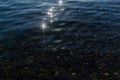 sun glare and green colorful pebbles in the clear blue water of lake baikal, ripples, shore Royalty Free Stock Photo