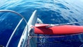 Sun glare reflected in blue sea water overboard of a moving boat