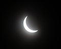 Partial solar eclipse with moon blocking sun, sun shining in a crescent shape in black sky Royalty Free Stock Photo