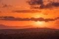 The sun glows behind purple clouds in an intense orange red sky