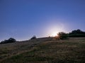 Sun going down behind a hill and on the horizon are two tiny silhouettes of people Royalty Free Stock Photo