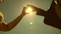 Sun in hand. Silhouette of a loving couple making a heart symbol with their hands opposite the sun on the horizon Royalty Free Stock Photo