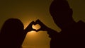 Sun in hand. teamwork of a loving couple. couple in love shows heart symbol with hands. Bride and groom making a heart