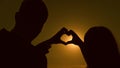 Sun is in the hands. A girl and her boyfriend making a heart shape by the hands opposite a beautiful sunset on the Royalty Free Stock Photo