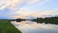 The sun has hidden behind the trees growing on the river bank. The colorful cloudy sky at sunset in summer is reflected in the wat Royalty Free Stock Photo