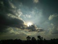 Sun hiding behind black clouds in blue sky background, beautiful sunset scenery view, weather conditions, nature photography