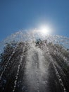 The sun illuminates a fountain jet spurting upwards against the background of the blue sky Royalty Free Stock Photo