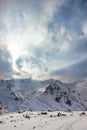 The sun illuminates snow mountains. Clouds close the sky Royalty Free Stock Photo
