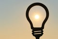 Sun inside the silhouette of a light bulb at sunset. Space for text. Royalty Free Stock Photo