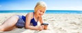 Smiling blond girl on seashore viewing photos on camera Royalty Free Stock Photo