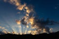 Sun light rays shining through dark clouds over mountains Royalty Free Stock Photo