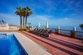 Sun lounger and beach umbrellas near pool over Mediterranean sea Royalty Free Stock Photo