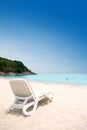 Sun lounger on sandy beach against blue sky