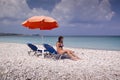 Sun lounger and umbrella on empty rock beach Royalty Free Stock Photo