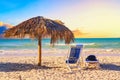 A sun lounger under an umbrella on the sandy beach by the sea and sky during sunset. Vacation background. Idyllic beach landscape Royalty Free Stock Photo