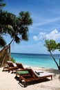 Sun loungers with beach and palm trees next to the sea in the Maldives Royalty Free Stock Photo