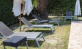 Sun loungers by the Hotel pool. A Place to Relax After Work. Comfortable Armchairs and Sun Umbrellas Against the Backdrop of Green Royalty Free Stock Photo