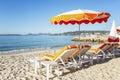 Sun loungers with orange mattresses on a sandy beach on the background of a calm blue sea. Idyll and relaxation. Space for text Royalty Free Stock Photo