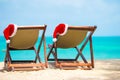 Sun loungers with Santa Hat at beautiful tropical beach with white sand and turquoise water. Perfect Christmas vacation