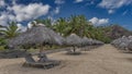 Sun loungers stand in rows under straw sun umbrellas on the sandy beach. Royalty Free Stock Photo