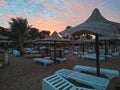 Sun loungers and straw umbrellas and beautiful sunset on the beach of Hurghada, Egypt Royalty Free Stock Photo