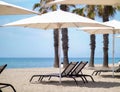 Sun loungers under white beach umbrellas near the sea, vacation concept Royalty Free Stock Photo