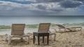 Sun loungers and a wicker table stand on the sandy beach. Royalty Free Stock Photo