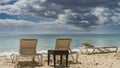 Sun loungers and a wicker table stand on the sandy beach.