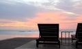 Sun lounges overlooking infinity pool and beach at sunset in a tropical resort