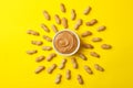 Sun made of peanut and bowl of peanut butter on yellow background