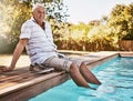 The sun is out and I feel good. a happy senior man dipping his feet in a swimming pool. Royalty Free Stock Photo