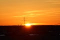 Sun over the horizon and television antenna in the background clouds in the orange sky at sunset or dawn backlit by the Royalty Free Stock Photo