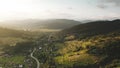 Sun over mountain village aerial. Houses at road with cars. European town. Countryside buildings
