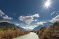 Sun over rural river between mountains