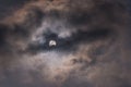 The sun during a partial solar eclipse with dark clouds .