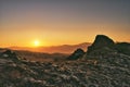 Sun peaking over the mountains in germany beside a large rock formation Royalty Free Stock Photo