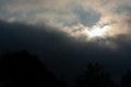 Sun peeks out through a dark storm cloud on a cloudy day as a thunderstorm and storm is approaching. Royalty Free Stock Photo
