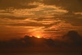 The sun peeping over the cloud in a vibrant picturesque tropical orange red coloured sunrise seascape Royalty Free Stock Photo