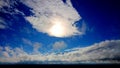 Sun poking through the clouds against a very blue cloudy sky Royalty Free Stock Photo