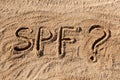 Sun protect factor concept. SPF word written on the beach with question mark