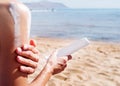 Sun protection cosmetics. Caucasian woman applying sun cream sunbathing on beach Royalty Free Stock Photo