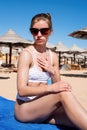 Sun protection cosmetics. Caucasian woman applying sun cream sunbathing on beach Royalty Free Stock Photo