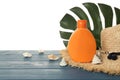 Sun protection cream, hat, leaf and sea shells on blue wooden table Royalty Free Stock Photo