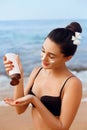 Sun Protection, girl using sunscreen to safe her skin healthy. Sexy young woman in bikini holding  bottles of sun cream in her han Royalty Free Stock Photo