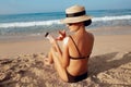 Sun Protection, girl using sunscreen to safe her skin healthy. Sexy young woman in bikini holding  bottles of sunscreen in her han Royalty Free Stock Photo