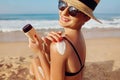 Sun Protection, girl using sunscreen to safe her skin healthy. Sexy young woman in bikini holding  bottles of sunscreen in her han Royalty Free Stock Photo