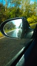 sun and rain on the way. view in the side rearview mirror on a wet paved road illuminated by the sun