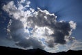 Sun rays behind clouds above mountains Royalty Free Stock Photo